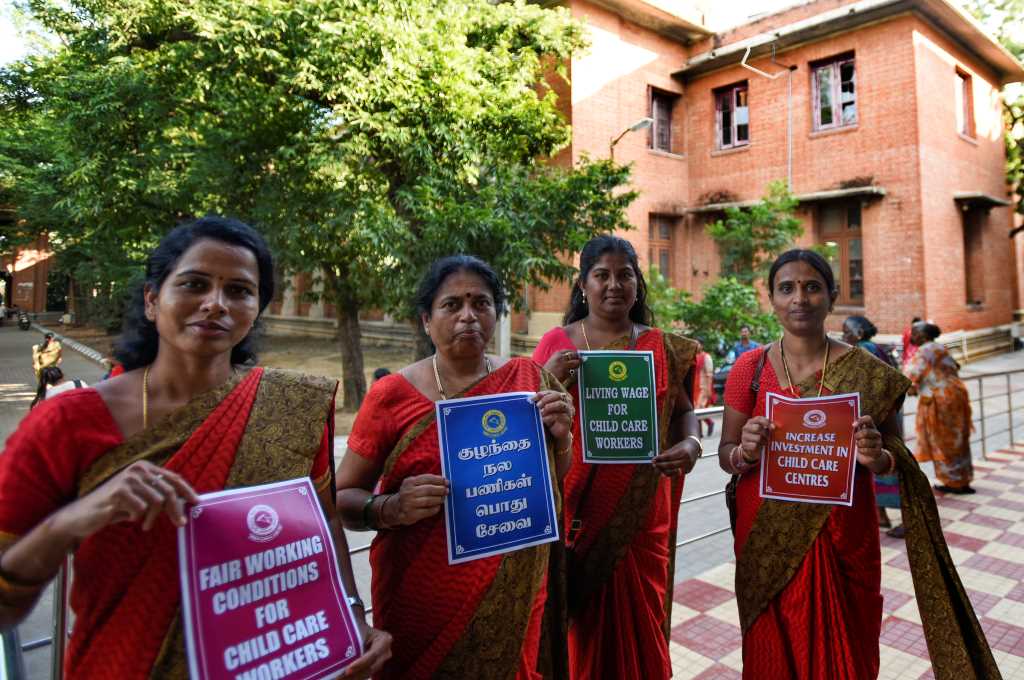 Four women standing with posters demanding better working conditions_social welfare