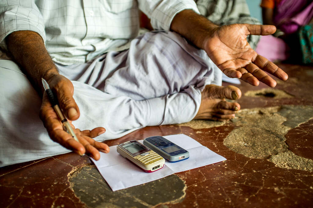 A man sits crosslegged before two old cellphones-digital divide