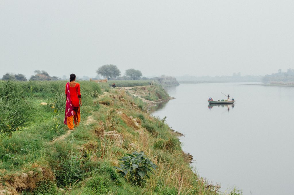 a woman farmer walking along a rive-land rights