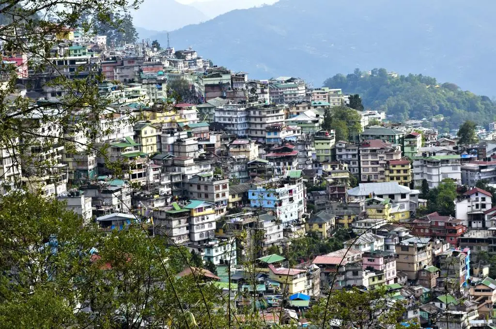 The image is a zoomed-out view of a town built on a hill and features many colourful buildings and other hills in the background._wastewater