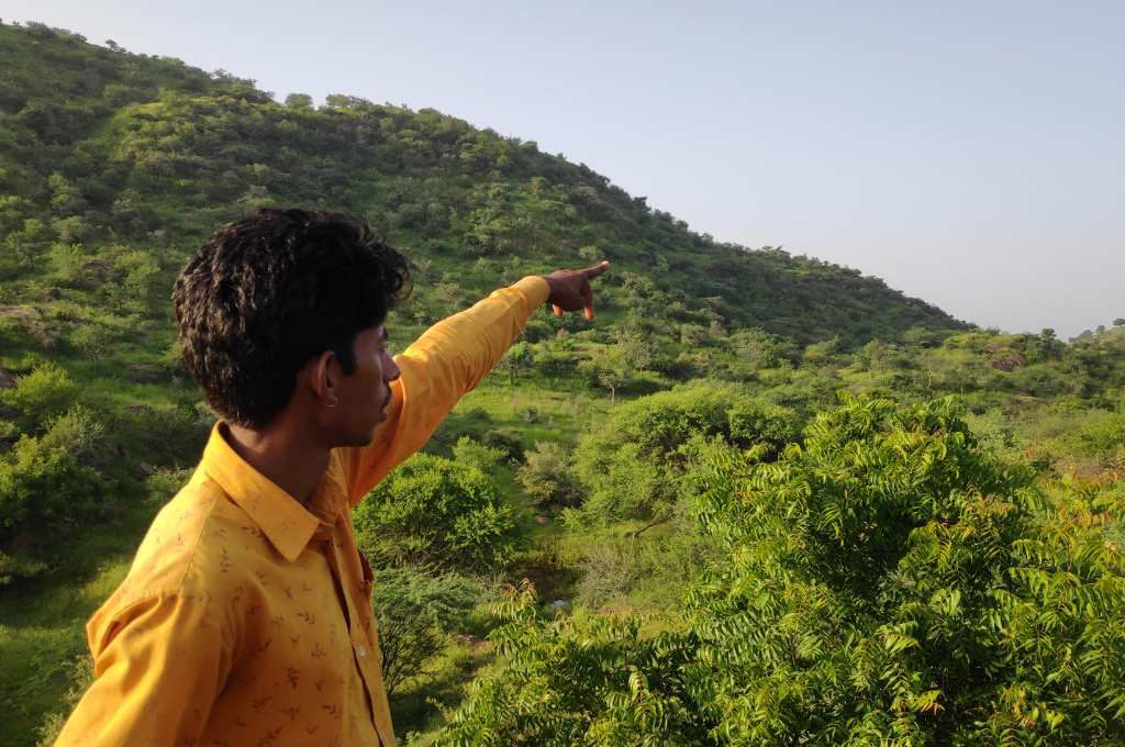 a young man points towards a grassy hill--common land