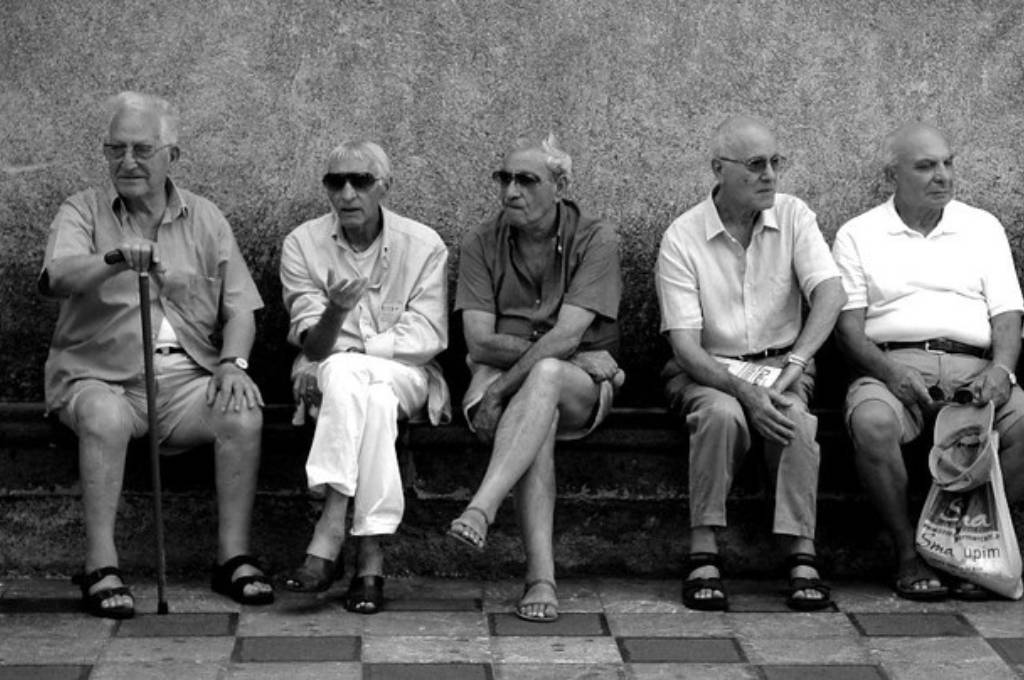 a group of old men sitting on a bench against the wall_nonprofit humour