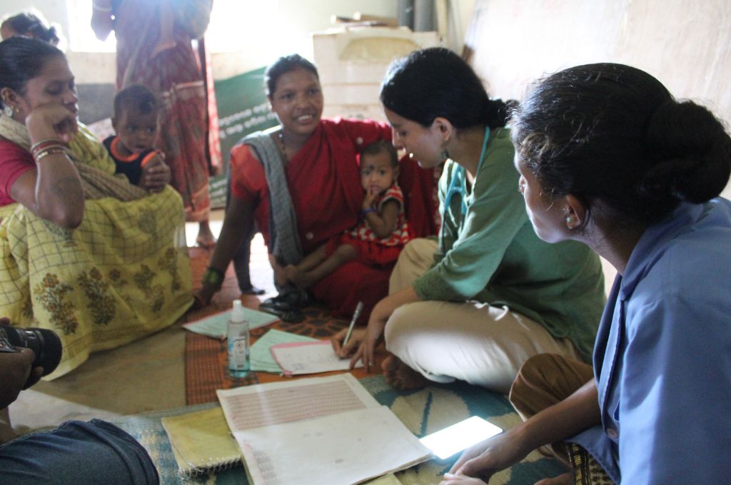 A doctor sitting with women and children_maternal health