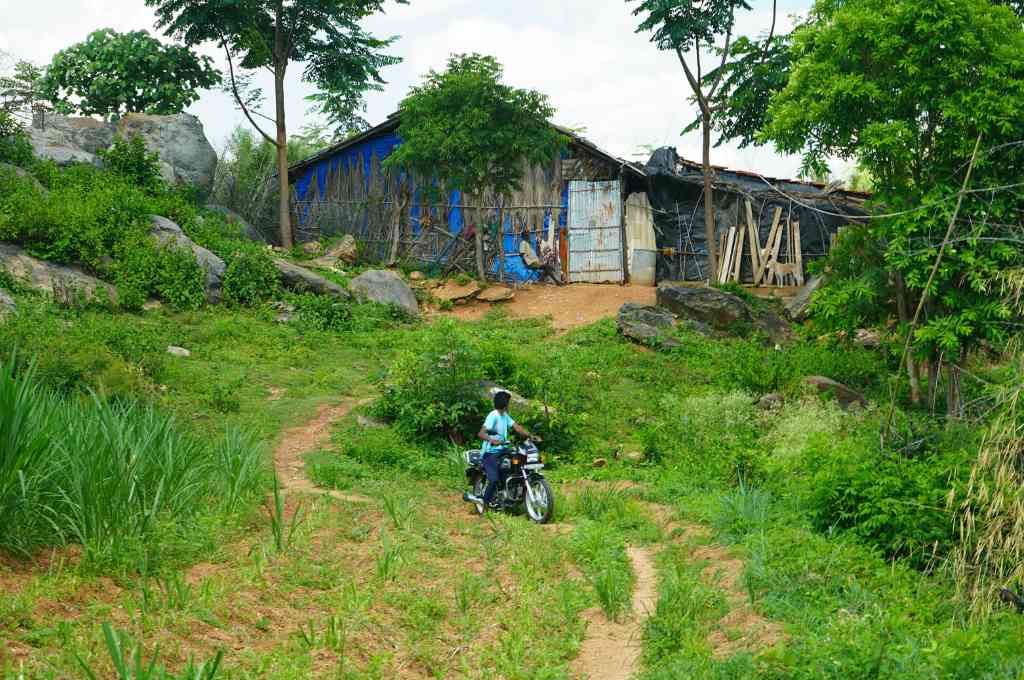 a young boy riding a motorcycle with a house in the background--bannerghatta conservation