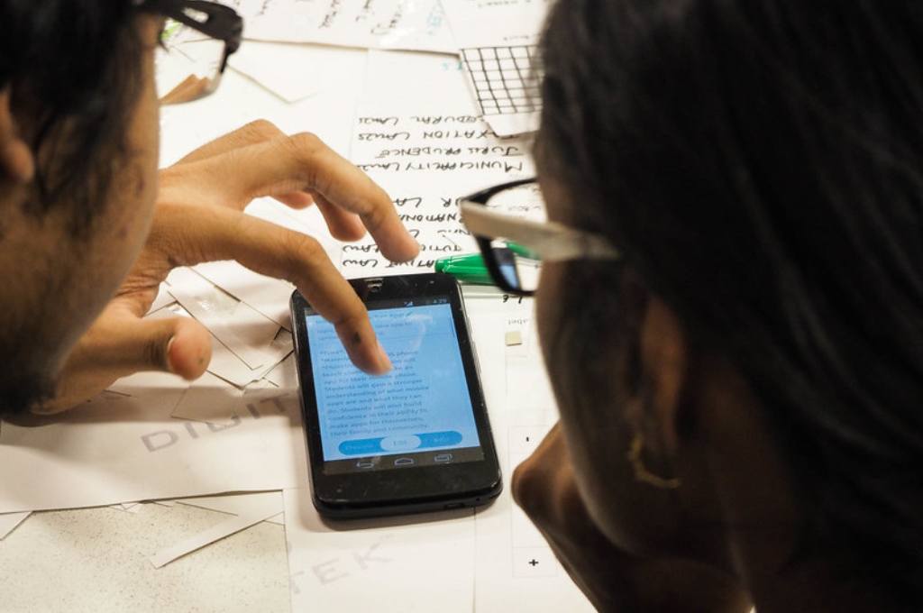 two people looking at a mobile phone-female enumerators