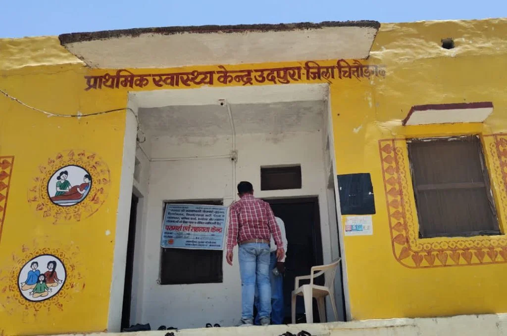 a man standing in front of a yellow primary health centre-pregnancy