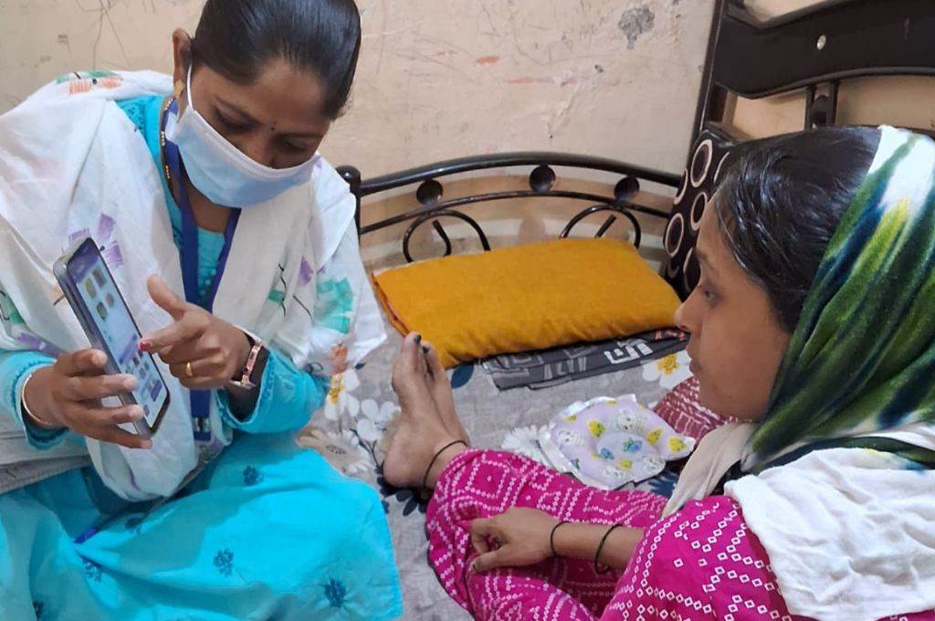 a woman wearing a medical mask showing another woman apps on a mobile phone-technology