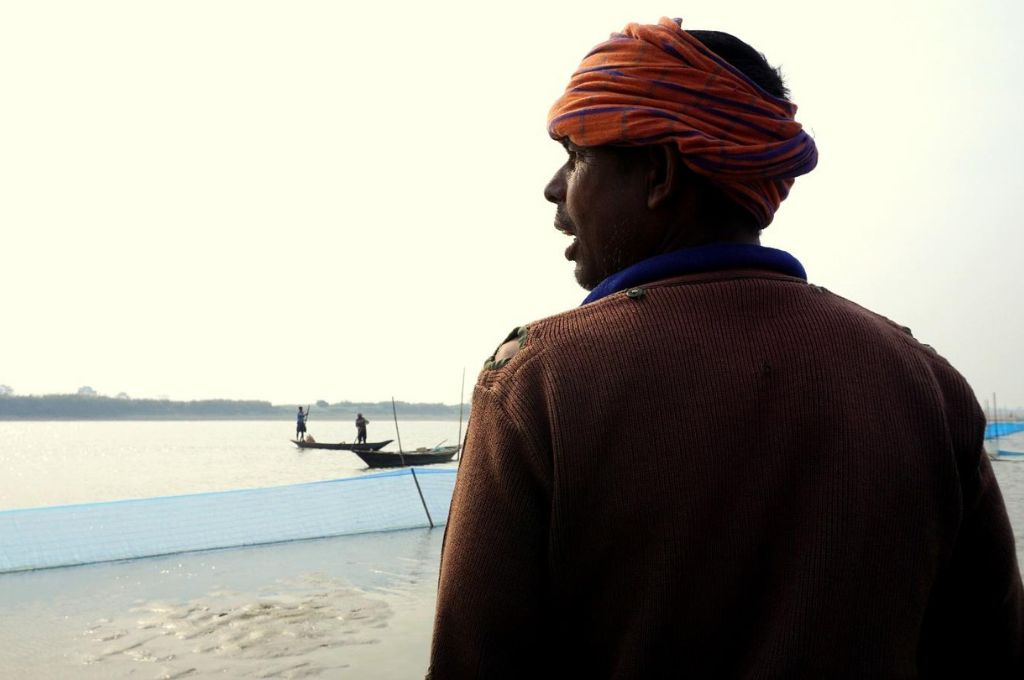 a fisherman with his back to the camera, and the brahmaputra in the background--Life of the Kaibarta fishing community in Assam