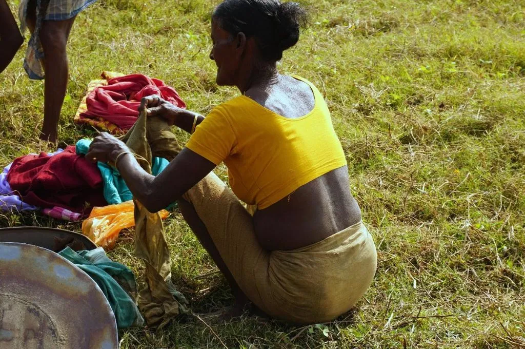 a woman changing into fishing-appropriate clothing before going fishing in assam--Life of the Kaibarta fishing community in Assam