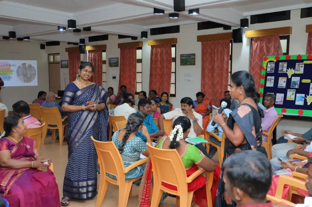 A woman speaking on a mic to a group of people in a workshop_integrating tech 