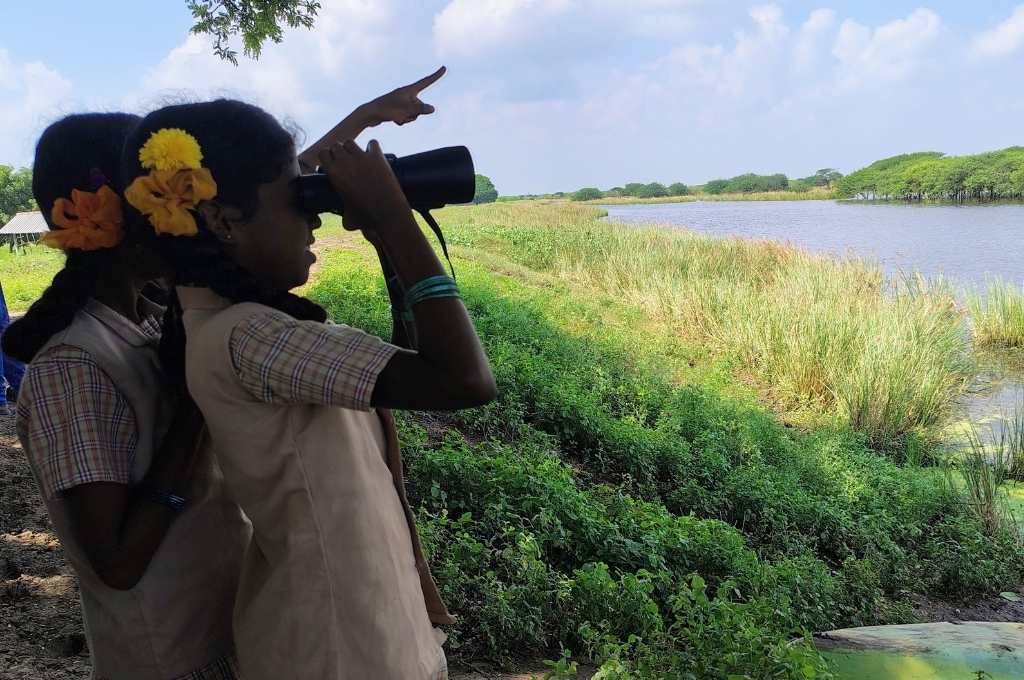 two children looking through binoculors at a beautiful lake-biodiversity