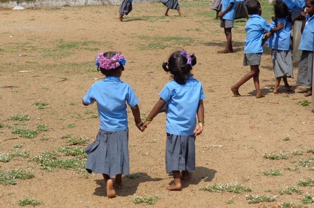 Two school children holidng hands and walking in a ground_denotified tribes