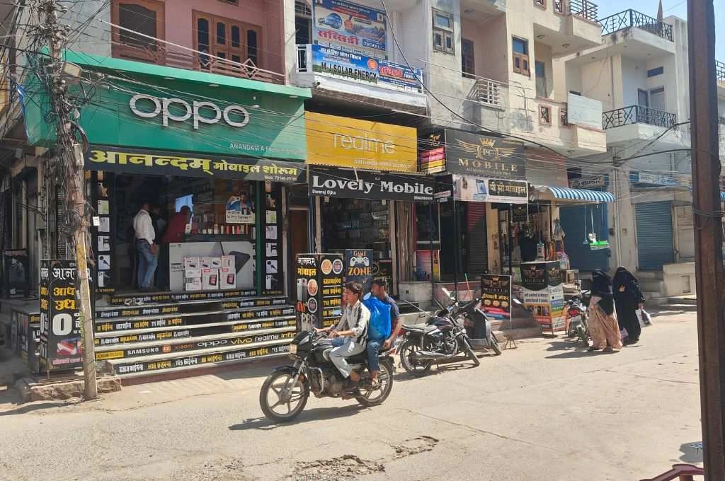 People pass by mobile shops on a road._E-waste management