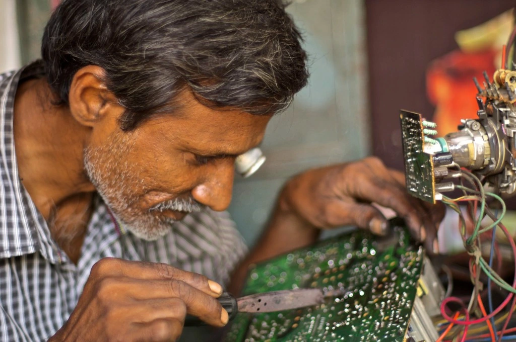A man repairs a circuit board._E-waste management