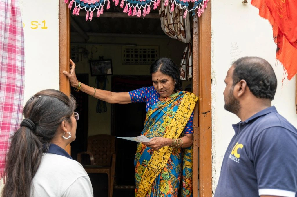 two community mobilisers providing a pamphlet to a woman-skill training
