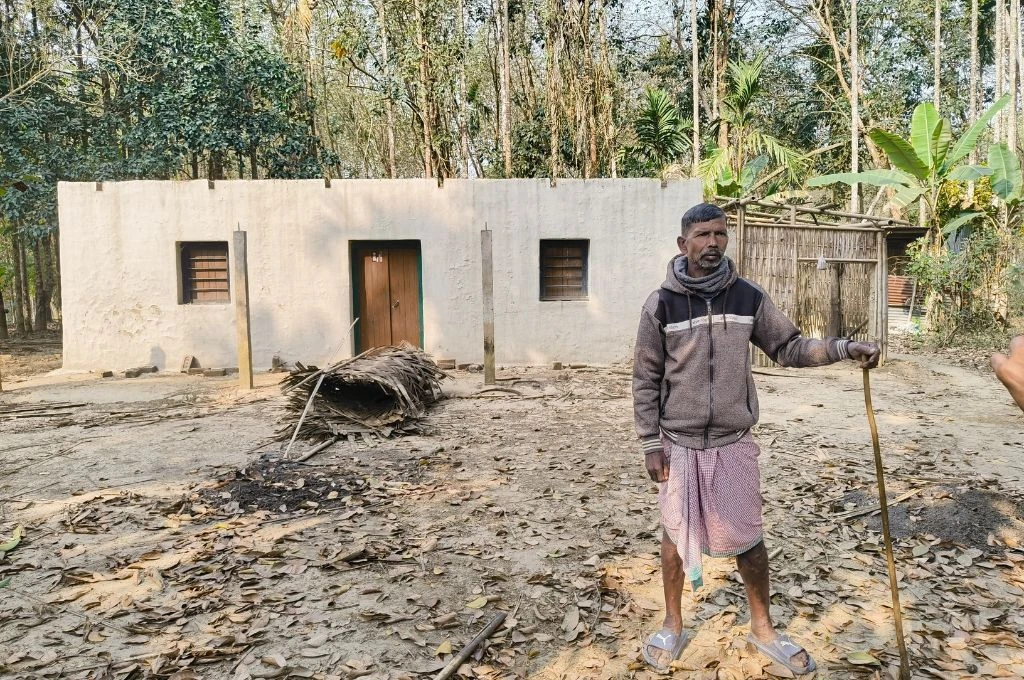 A man, Sukhram Gour, standing in front of his house_rubber plantation