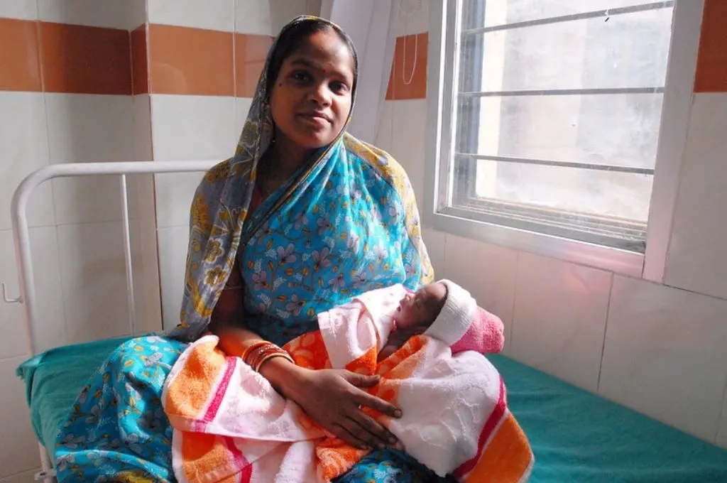 a young woman sitting on a hospital bed with a baby-midwives