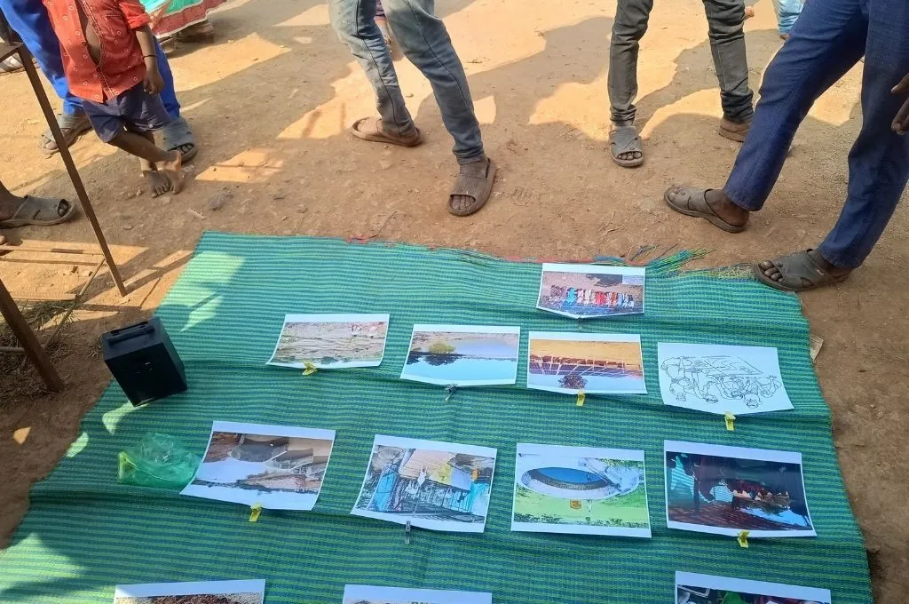 people standing around an information desk set up on the ground--community participation