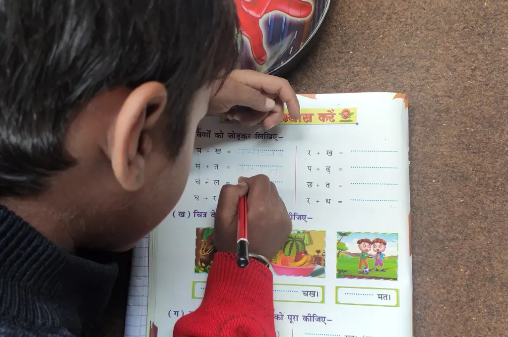 a close up of a kid reading and writing in a workbook-language education
