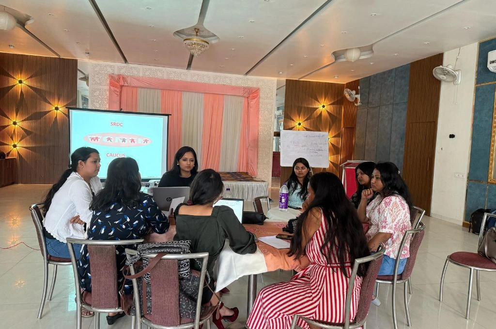 A group of women sitting on a circular table and discussing work_gender and inequality 