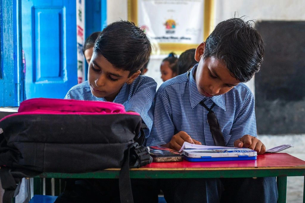Two children sitting at their desk in a classroom_climate education