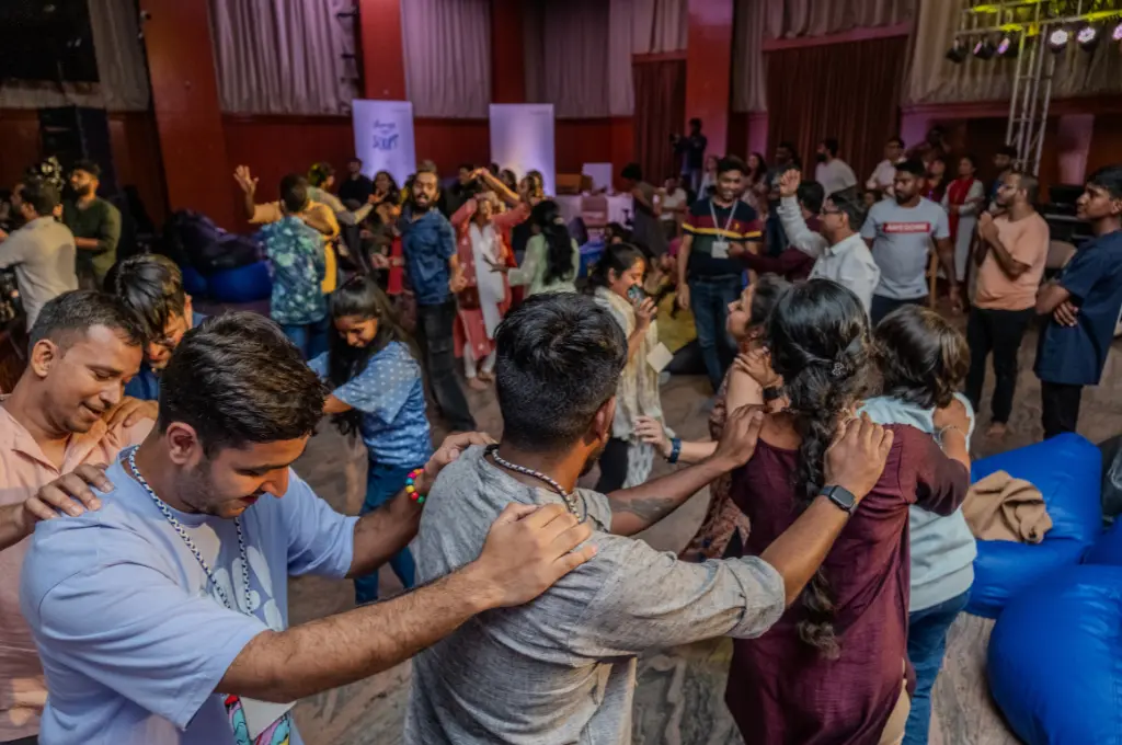 Participants form a circle with hands on each other's shoulders during an interactive session at a conference_disability