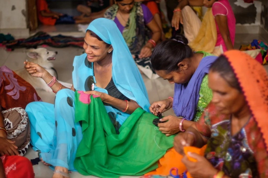 The image features a group of women sitting together and stitching appliques on a piece of fabric._ONDC platform