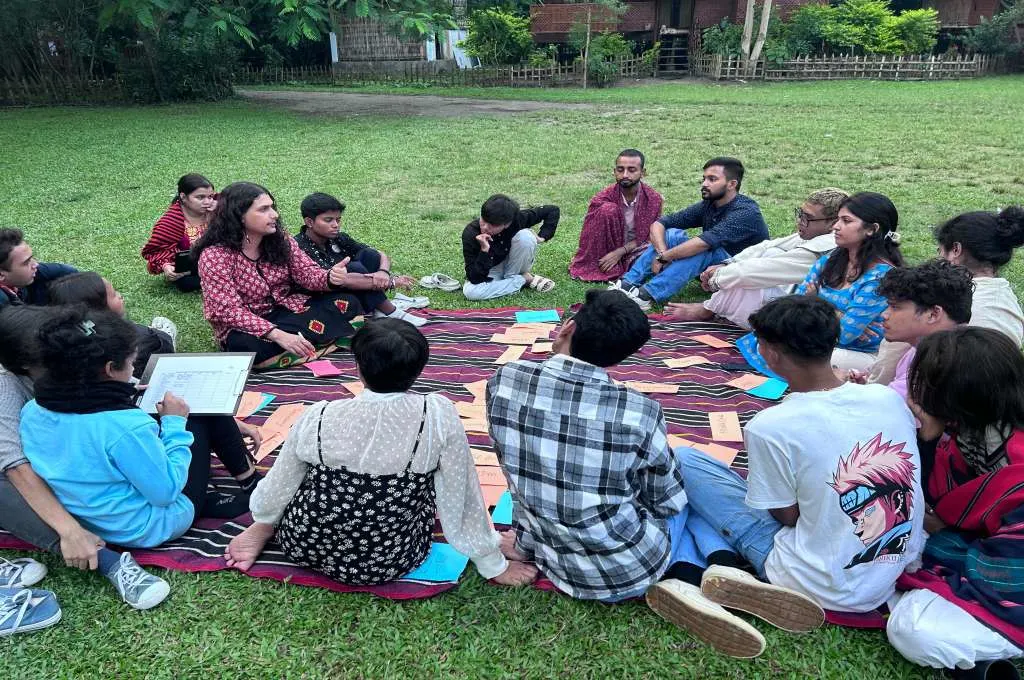 The image features a group of people sitting in a circle and having a discussion._Queer inclusion