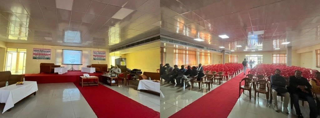 A public hearing venue is shown with a stage, chairs, and a projector screen at the front. The hall is largely empty, with only a small group of attendees seated towards the middle and back, while most chairs remain unoccupied_envionrment impact assessment
