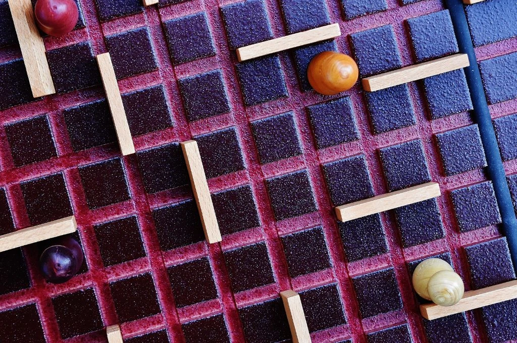 A board game with a red and black grid, wooden pawns of different colors, and small wooden walls placed across the squares_mental health for lgbt