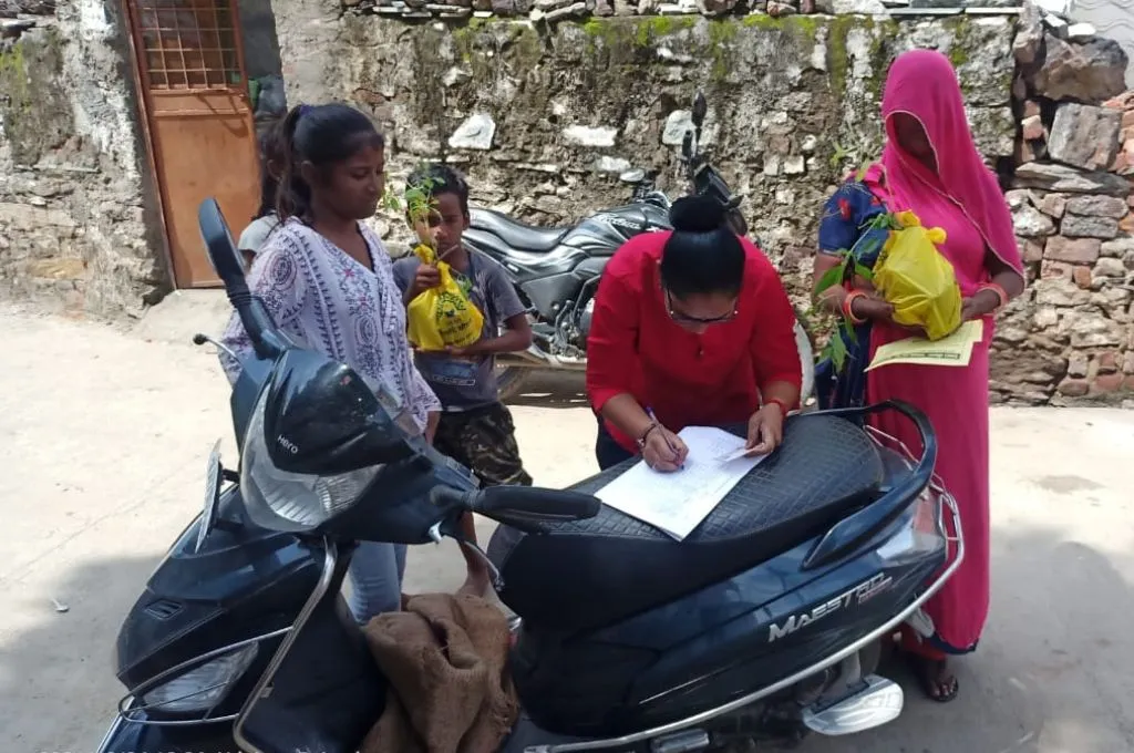 a female forest guard surrounded by three children and a woman fills out a form on a scooter--forest guard