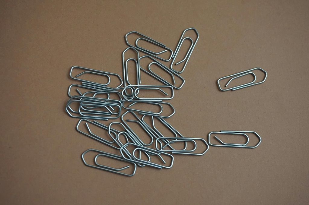 a bunch of about 50 paper clips lying on a brown surface-12A 80G