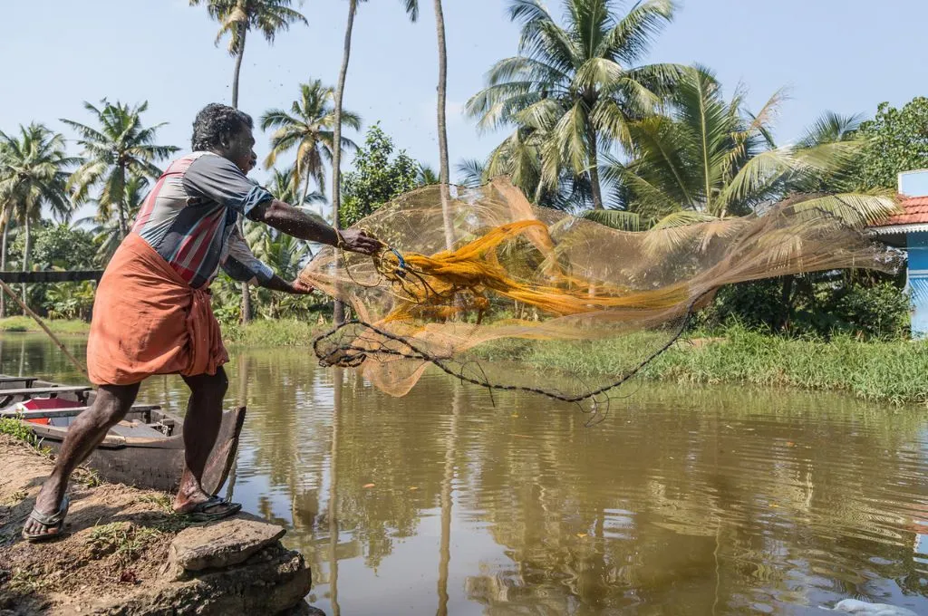 A man throws his fishing net in a water body_Commons