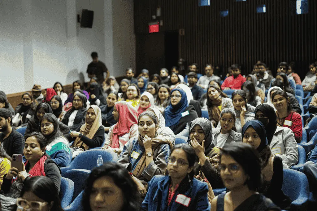 a large group of women seated in an auditorium and focused on the front of the room--marginalised women