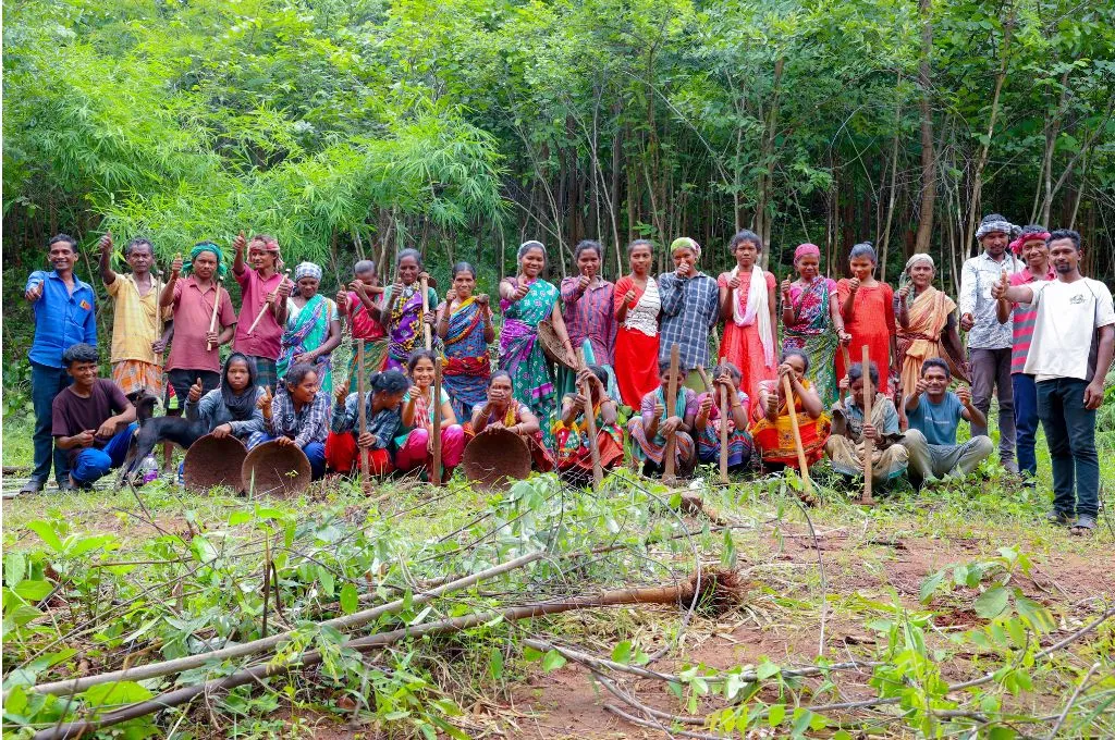 a group of farmers standing in a field with their thumbs up facing the camera, with trees in the background--commons governance