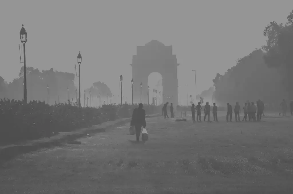 a greyscale image of india gate, new delhi, with some people in the foreground and a thick smog everywhere--nonprofit humour